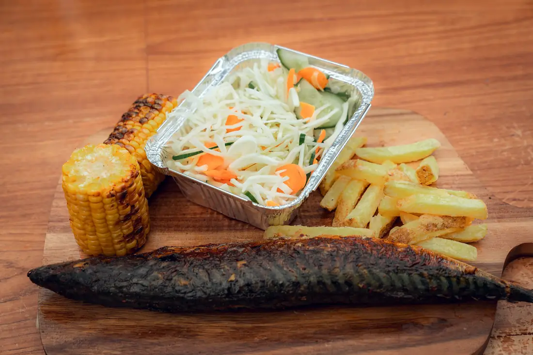 Mackerel meal with chips, salad, and roasted corn