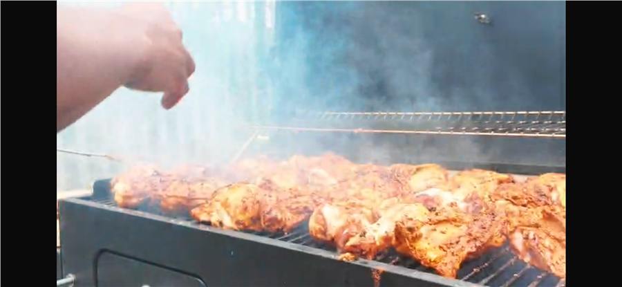 Chicken cooking over charcoal with smoke rising