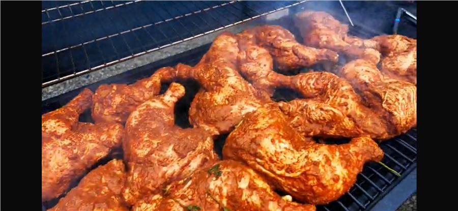 Marinated chicken grilling over charcoal